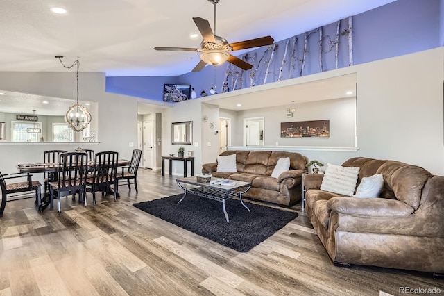 living room with high vaulted ceiling, wood finished floors, and ceiling fan with notable chandelier
