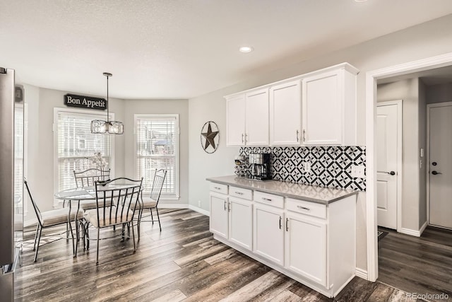 kitchen featuring dark wood-style flooring, white cabinetry, baseboards, backsplash, and pendant lighting