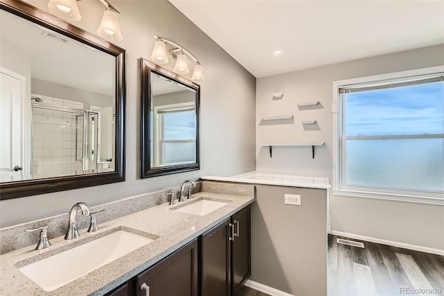 bathroom featuring double vanity, visible vents, a sink, and wood finished floors