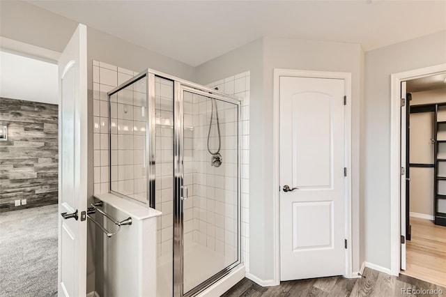 bathroom featuring an accent wall, a stall shower, baseboards, and wood finished floors