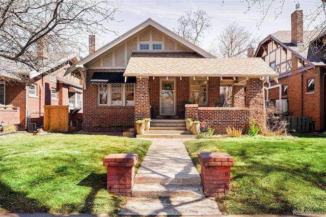 view of front facade with covered porch, brick siding, a chimney, and a front yard