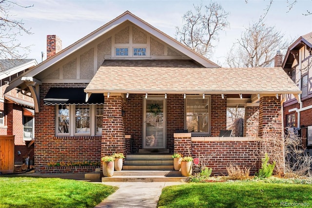 view of front of property with brick siding, a shingled roof, a chimney, and stucco siding