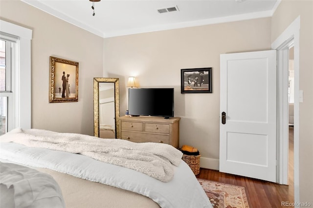 bedroom with baseboards, dark wood-style flooring, visible vents, and crown molding