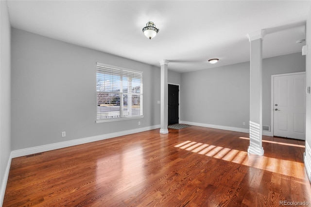 empty room featuring decorative columns and wood-type flooring