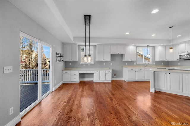 kitchen featuring hanging light fixtures, hardwood / wood-style flooring, sink, and white cabinets