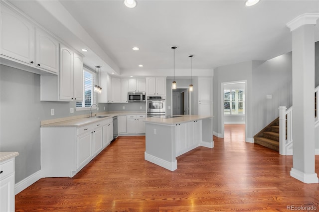 kitchen featuring stainless steel appliances, a center island, pendant lighting, and white cabinets