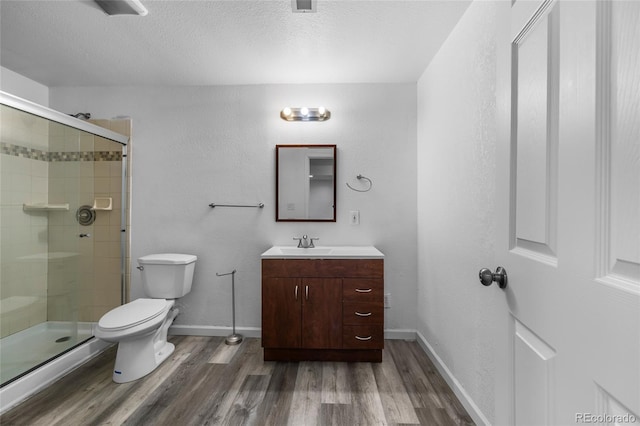 bathroom featuring toilet, an enclosed shower, a textured ceiling, vanity, and hardwood / wood-style floors