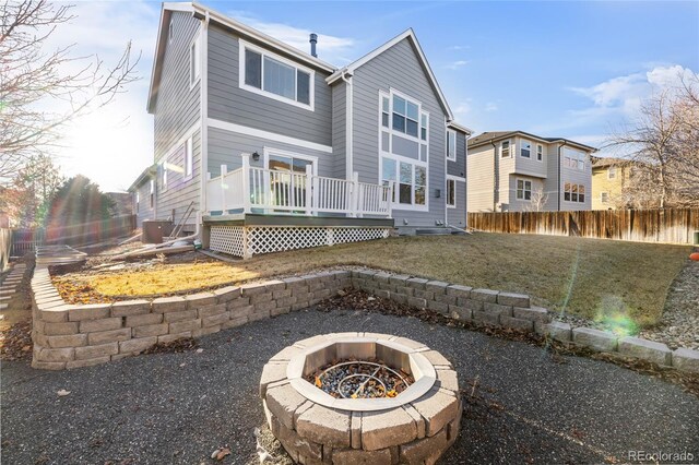 rear view of property with a wooden deck, a yard, central AC unit, and a fire pit