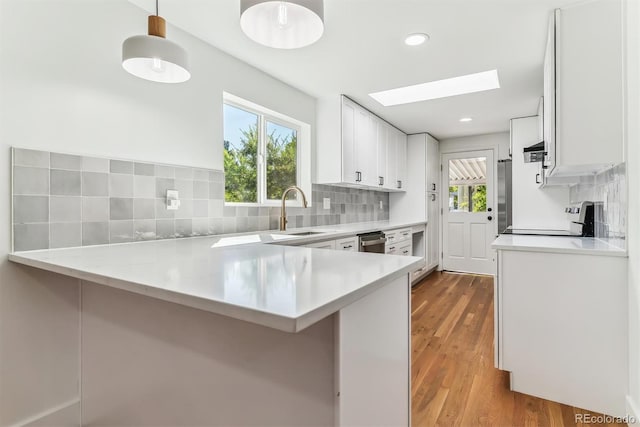 kitchen featuring pendant lighting, kitchen peninsula, stainless steel range, and white cabinetry