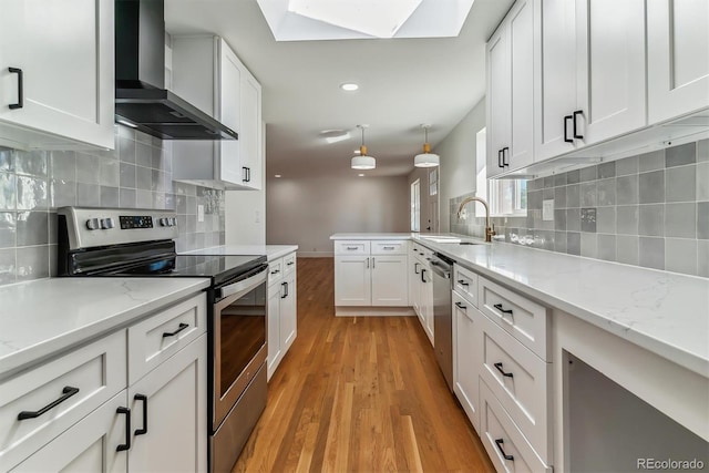 kitchen featuring wall chimney exhaust hood, white cabinets, and appliances with stainless steel finishes