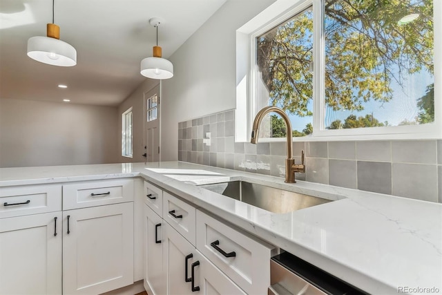 kitchen with light stone countertops, decorative light fixtures, and white cabinetry