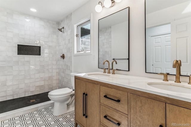 bathroom featuring vanity, tile patterned floors, toilet, and tiled shower