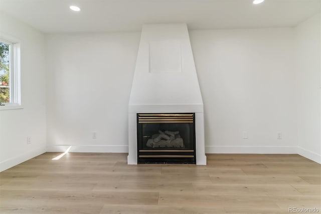 unfurnished living room with a large fireplace and light hardwood / wood-style flooring