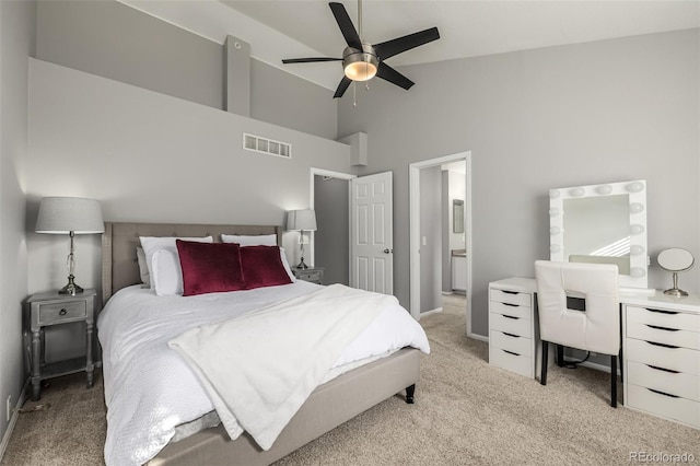 bedroom with ceiling fan, ensuite bathroom, high vaulted ceiling, and light carpet