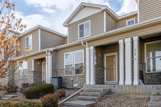 9758 Laredo St Unit 37C, Commerce City, CO 80022 - property entrance featuring cooling unit, stone siding, and covered porch