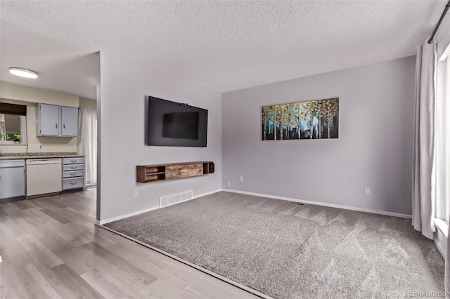 2212 S Naples Way, Aurora, CO 80013 - unfurnished living room featuring a textured ceiling, wood finished floors, plenty of natural light, and carpet