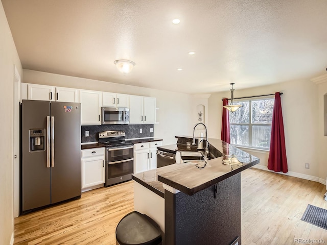 kitchen featuring appliances with stainless steel finishes, pendant lighting, and white cabinets