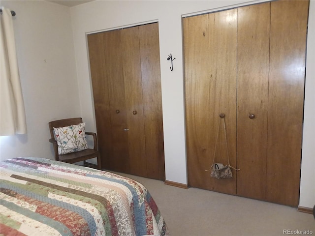 carpeted bedroom with two closets and baseboards