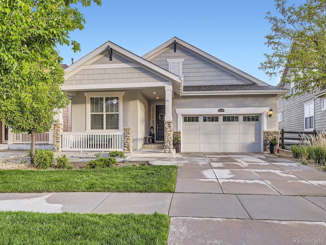 18280 W 85th Dr, Arvada, CO 80007 - view of front of home featuring stucco siding, stone siding, concrete driveway, an attached garage, and a porch