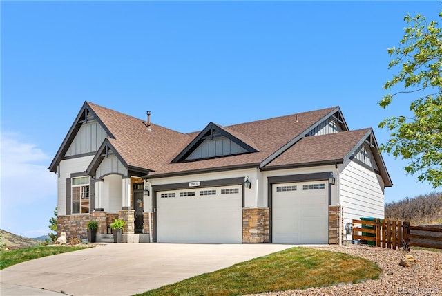 craftsman-style house featuring board and batten siding, roof with shingles, fence, an attached garage, and stone siding