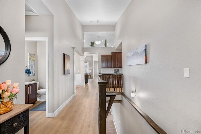 corridor featuring baseboards, a high ceiling, and light wood finished floors