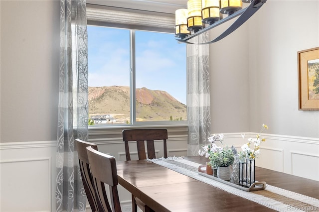 dining area with a mountain view, a decorative wall, and a wainscoted wall