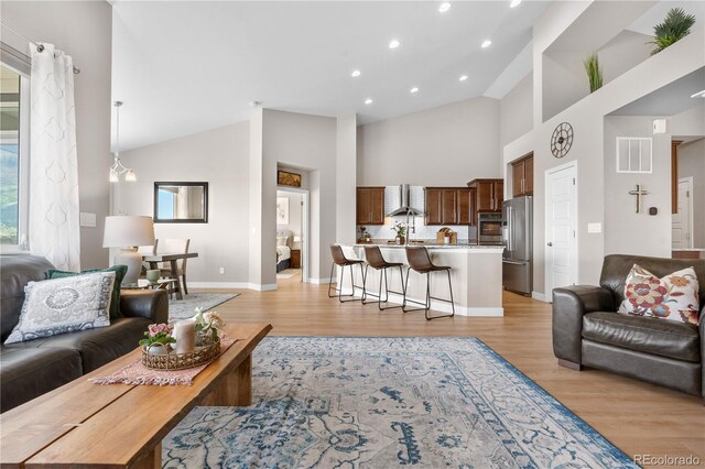 living room featuring visible vents, baseboards, light wood-style floors, high vaulted ceiling, and recessed lighting