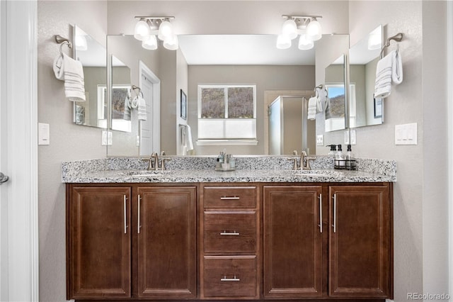 full bathroom featuring double vanity, a sink, and a shower with door