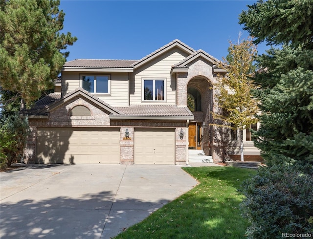 traditional-style house with a garage, driveway, brick siding, a tile roof, and a front yard