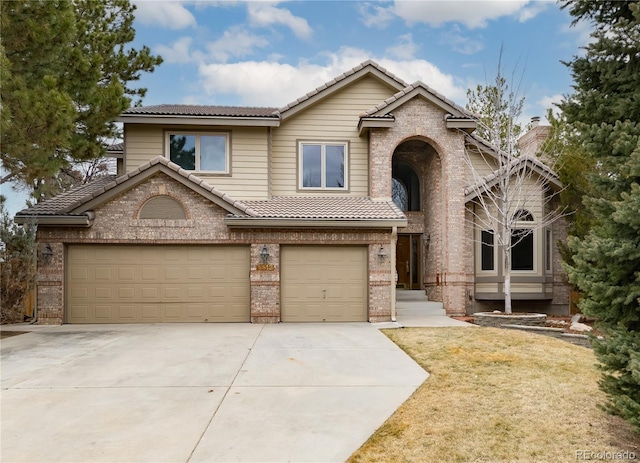 view of front facade with brick siding, concrete driveway, a tile roof, an attached garage, and a front yard