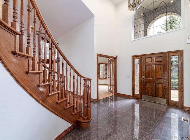 foyer entrance featuring visible vents, granite finish floor, stairway, a high ceiling, and baseboards