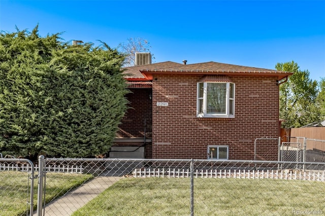 view of side of home featuring a lawn, fence, and brick siding