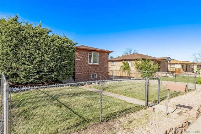 exterior space with fence, a gate, brick siding, and a front yard