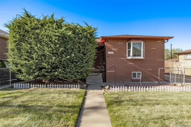 view of front facade featuring brick siding, fence, and a front lawn