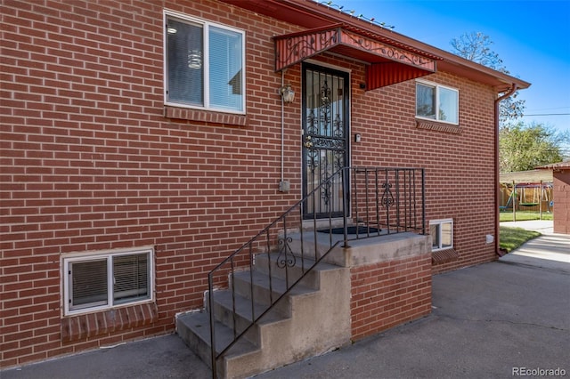 doorway to property with brick siding and visible vents