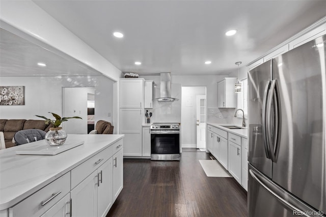 kitchen featuring wall chimney range hood, dark wood finished floors, a sink, open floor plan, and stainless steel appliances