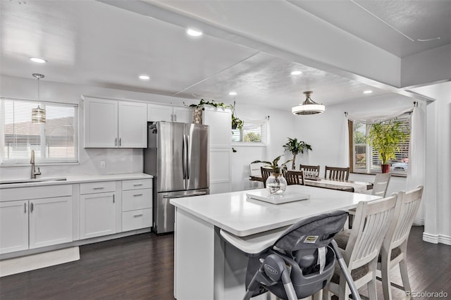 kitchen with a sink, a breakfast bar area, light countertops, freestanding refrigerator, and recessed lighting