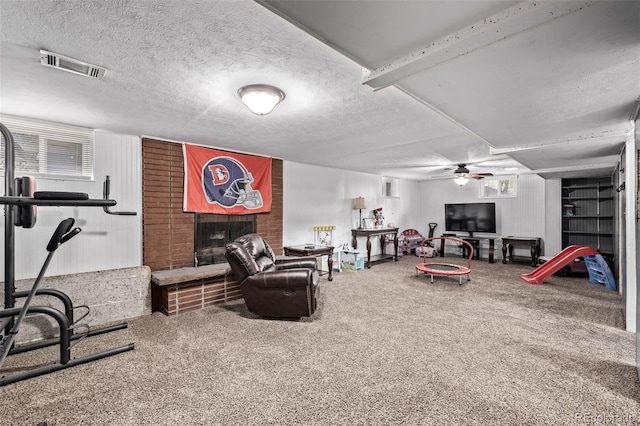 carpeted living area with a brick fireplace, a ceiling fan, a textured ceiling, and visible vents