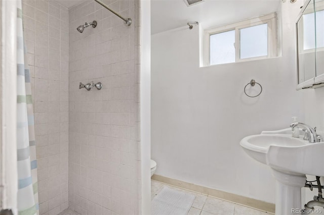 bathroom with toilet, a wealth of natural light, tiled shower, and tile patterned flooring