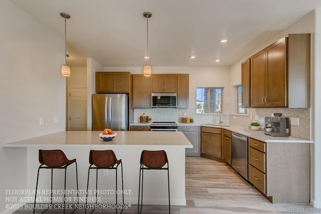 881 W 128th Pl, Westminster, CO 80234 - kitchen featuring stainless steel appliances, a peninsula, a kitchen bar, tasteful backsplash, and light countertops