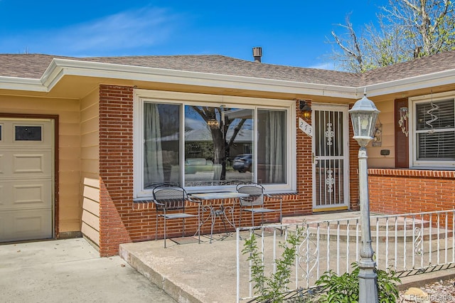 273 S 13th Ave, Brighton, CO 80601 - property entrance featuring covered porch, brick siding, and roof with shingles