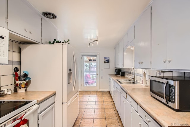273 S 13th Ave, Brighton, CO 80601 - kitchen featuring a sink, light countertops, light tile patterned floors, stainless steel microwave, and white cabinetry
