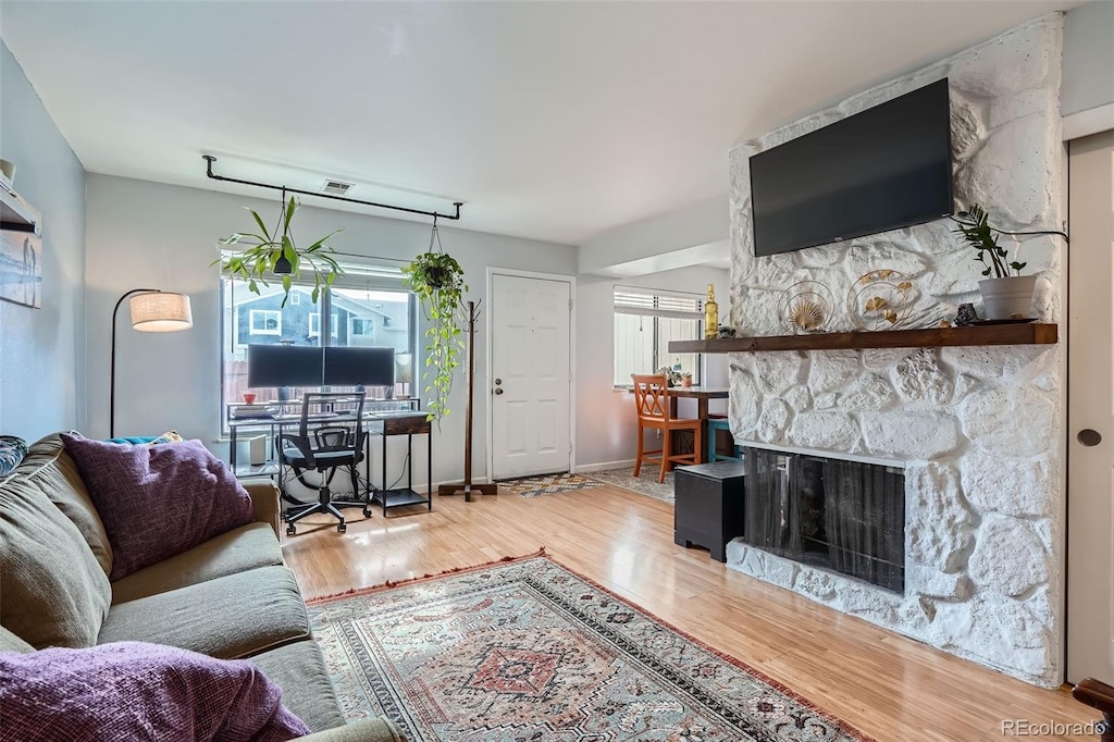 living room featuring hardwood / wood-style floors and a stone fireplace