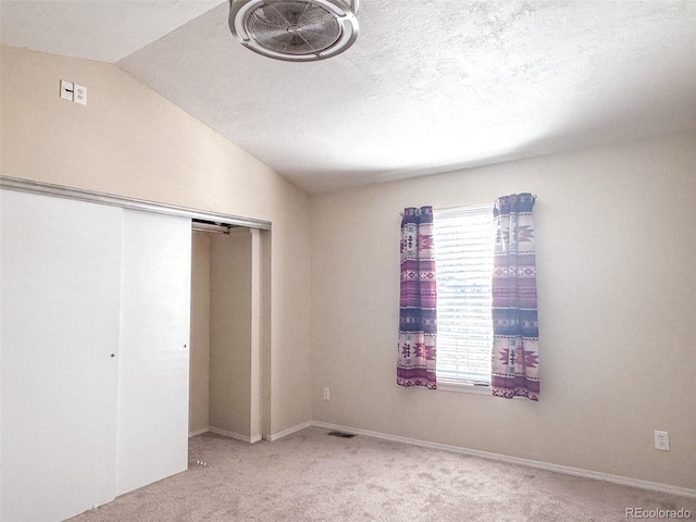 unfurnished bedroom with lofted ceiling, light colored carpet, and a textured ceiling