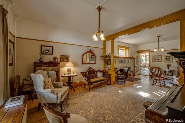 living area with a chandelier, hardwood / wood-style floors, and decorative columns