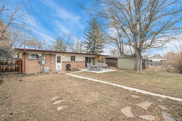 rear view of property featuring a storage unit and a patio area