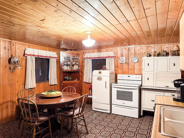 kitchen with fridge, sink, white range with electric stovetop, and wood walls