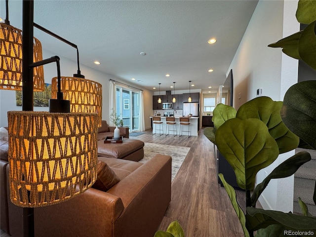 living room featuring light wood-style flooring, recessed lighting, and a textured ceiling