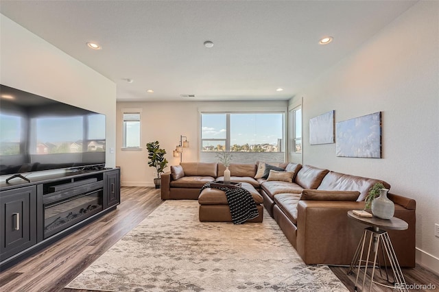 living room with recessed lighting, visible vents, baseboards, and wood finished floors