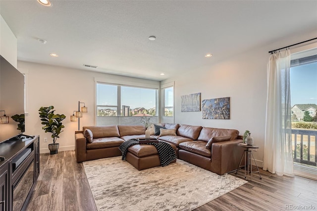 living area with recessed lighting, visible vents, a healthy amount of sunlight, and wood finished floors